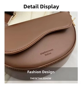 Detail of a brown leather saddle bag featuring a curved flap and golden embossed lettering