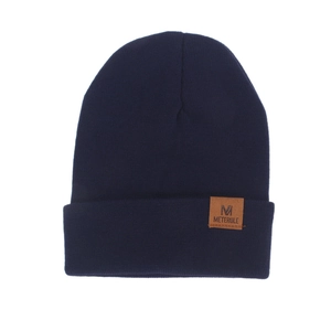Detail of navy knit beanie with premium brown leather logo patch on cuffed edge