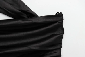 Macro detail of black satin fabric showing pleated texture and silky smooth finish