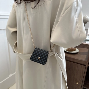 Chic geometric pattern square crossbody bag with gold chain strap on beige trench coat