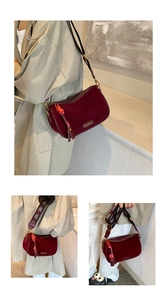 Detail of burgundy suede pillow bag featuring a woven wide strap and long tassel