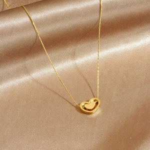 Collier élégant doré à double cœur suspendu présenté sur un tissu en soie champagne luxe