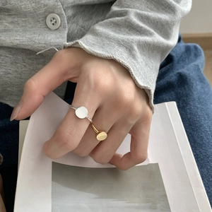 Detailed close-up of minimalist gold and silver round flat top rings on model fingers