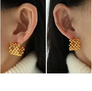 Close-up of gold-plated mesh sphere earrings showing intricate hollow beaded details