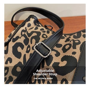 Detail of adjustable black leather strap with silver buckle on leopard print tote bag