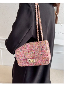 Pink tweed crossbody bag with gold chain strap worn by a model in a black coat