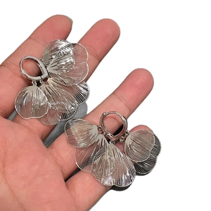 Silver hollow heart petal hoop earrings with brushed metallic texture held in hand