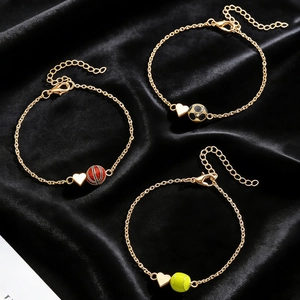Trois colliers de sport dorés avec pendentifs ballons et cœurs sur satin noir