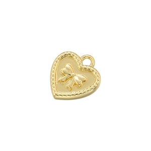 Detailed view of heart-shaped gold-plated copper pendant with relief bow and beaded edge