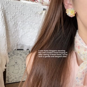 Close-up of hand-woven colorful flower stud earrings worn by a model in a garden style
