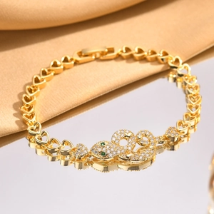 Detail of gold snake head bracelet with green gemstone eyes on champagne satin