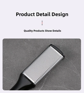 Detail of stainless steel grater with fine holes and ergonomic black handle on stone