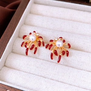 Detailed macro of gold-plated fireworks earrings with red petals and central pearl