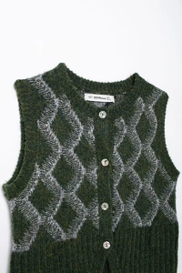 Détail du gilet en maille vert à losanges gris, avec boutons et étiquette du col