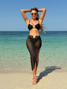 Dettaglio del bikini nero a tre pezzi con gonna lunga in rete e fibbia a stella marina dorata