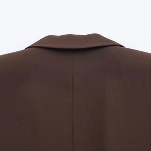 Detail of neckline and shoulder tailoring on a brown blazer with fine plain weave fabric