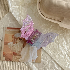 Detail of bat-shaped hair claw clip with pink purple gradient and glitter finish