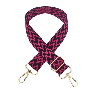 Close-up of pink and black geometric woven bag strap with golden rotating metal buckles