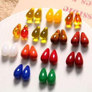 Macro view of colorful resin teardrop beads arranged in pairs on a white display tray