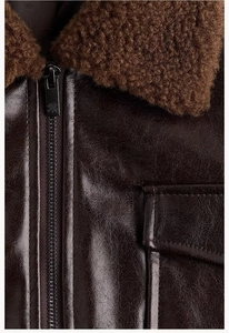 Detailed view of dark brown leather jacket featuring a plush faux shearling collar and zipper