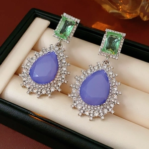 Détail macro de boucles d'oreilles vintage avec cristaux violets et verts dans un coffret