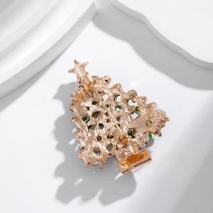 Rose gold Christmas tree brooch with green crystal inlay on a minimalist white background