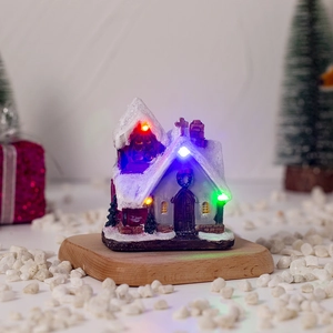 Detail of a glowing Christmas resin church house with colorful LED lights on wood