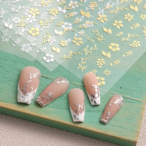 Detailed close-up of gold and silver cherry blossom nail stickers on wooden surface