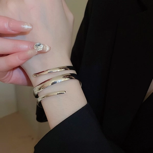 Close-up of a silver minimalist spiral wrap bangle worn over a black suit cuff