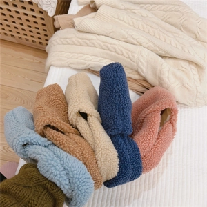 Bandeaux en laine d'agneau multicolores montrant une texture douce sur un couvre-lit