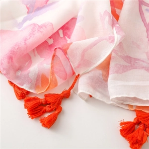 Close-up of vibrant watercolor floral print shawl with bright orange fringe tassels