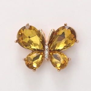 Macro view of crystal butterfly charm with yellow gemstones and gold finish for DIY