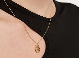 Close-up of a gold S925 silver necklace featuring an oval pendant with a colorful zircon X
