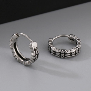 Close-up of vintage engraved stainless steel hoop earrings with intricate gothic patterns