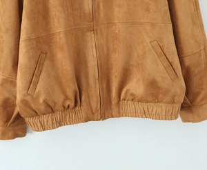 Detailed shot of brown suede jacket featuring metal zipper and elastic hemline