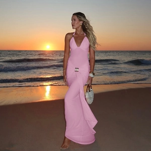 Robe longue rose à licou avec boucle métallique présentée sur une plage au coucher du soleil