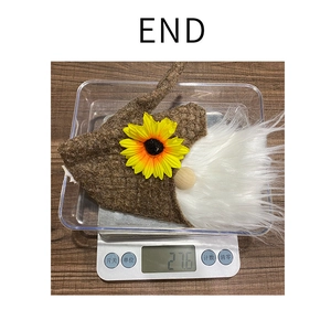 Close-up of a gnome wine bottle topper with sunflower detail on a digital scale