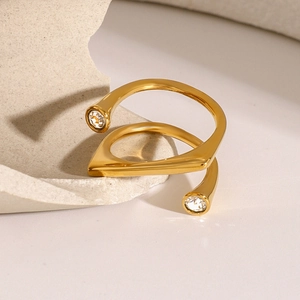 Detailed close-up of a double-layered gold ring with zircon accents on a stone surface