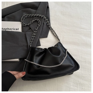 Detail of black pleated shoulder bag featuring elegant silver metal chain strap texture