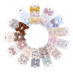 Flat lay of diverse bow hair clip sets in floral, solid, and polka dot fabric textures