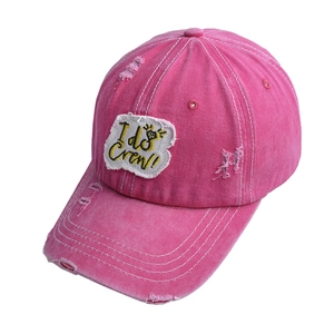 Detail of distressed rose red cotton baseball cap with I Do Crew embroidery and frayed edges