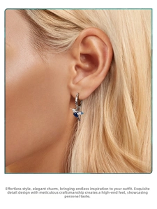 Detail of 925 silver hummingbird earring with blue crystals on model's ear
