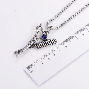 Detailed macro view of scissors and comb pendant with blue stone inlay and cm ruler scale