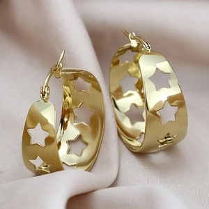 Detail of wide gold stainless steel hoop earrings with hollow star patterns on silk
