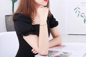 Detail shot of a minimalist gold padlock charm bracelet on a model's wrist