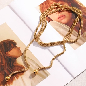 Detail of 18K gold plated multi-strand bead chain necklace with ball pendants on magazine