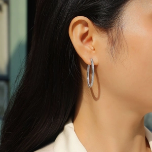 Close-up of silver hoop earrings with double row of moissanite stones on a model