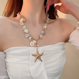 Detail of beaded necklace with gold starfish pendant and irregular white stones