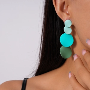 Close-up of geometric matte blue-green gradient hoop earrings worn by a model