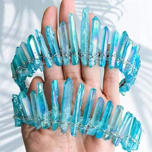 Macro shot of blue aura quartz crystal crown with silver wire wrap being held by hands